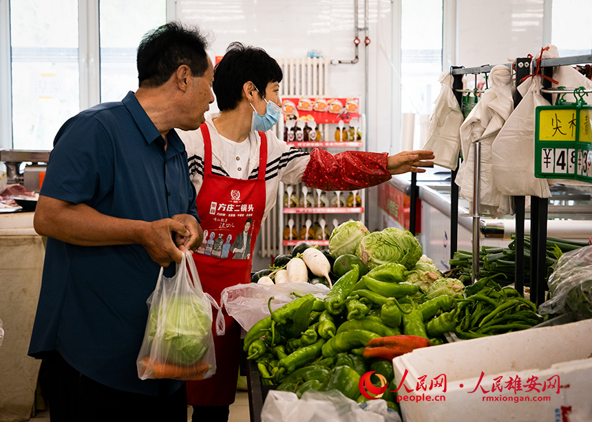 菜店內(nèi)，工作人員正在為顧客提供幫助。出門就是菜店，吃飯不發(fā)愁，成為容東片區(qū)居民的日常。人民網(wǎng)?宋燁文攝